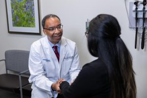 Faculty member smiling and shaking patients hand.