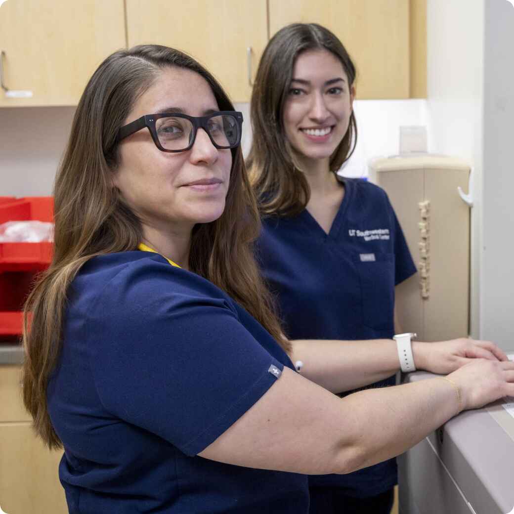 Two female nurses in blue scrubs working at a medical station in a hospital.