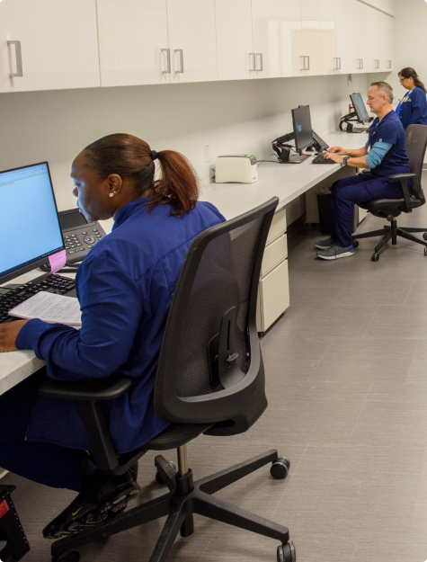 A group of operational support professionals looking at monitors while seated at a long desk 